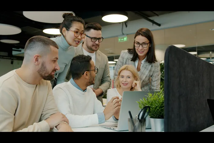 Zespół zgromadzony wokół laptopa w otwartym biurze